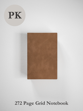 A portable pocket notebook featuring a textured, solid tan faux leather cover, ideal for grid note-taking.