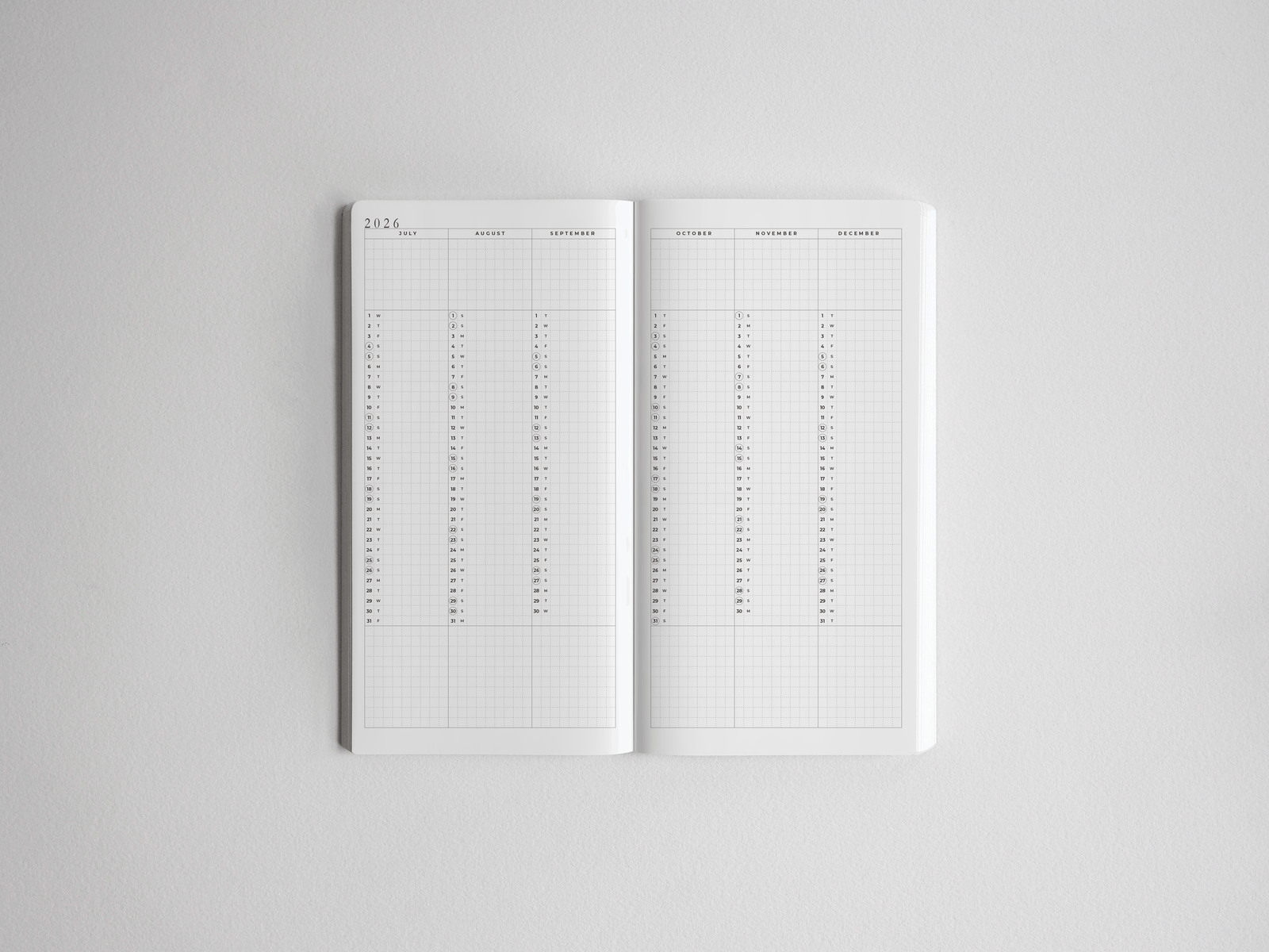 Open academic daily planner displaying structured monthly calendar spreads and ruled daily grids for comprehensive year-long planning from 2026 to 2027.