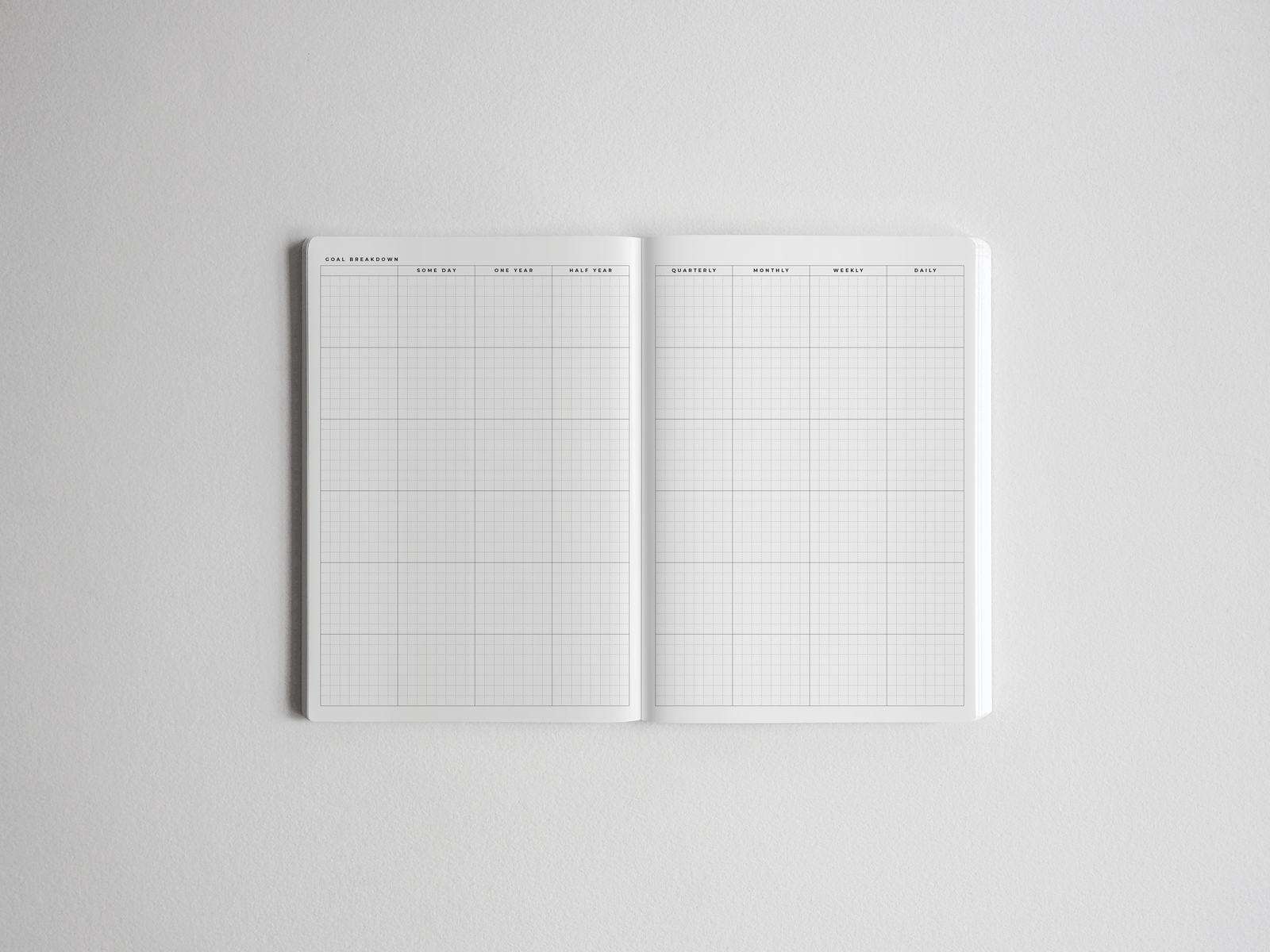 Minimalist academic planner open to two pages featuring light gray grid paper and structured headers for tracking goals, timelines, and yearly progress.