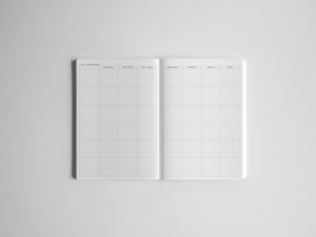 Open academic planner featuring comprehensive gridded white pages designed for yearly goal breakdown, quarterly tracking, and daily scheduling.