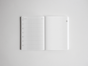 Open white academic planner showcasing organized study space, featuring lined sections for scheduling and structured grid graph paper for detailed note-taking.