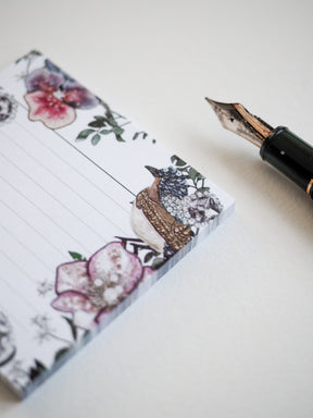 Watercolor sticky note adorned with lush pink florals, detailed green foliage, and a whimsical illustration of a small patterned bird.