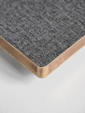 A close-up of a notebook or book corner showing a textured gray cover and white page edges on a light neutral background.
#Color_Tweed