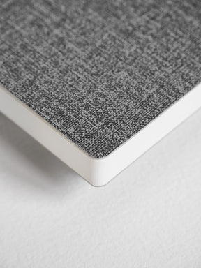A close-up of a notebook or book corner showing a textured gray cover and white page edges on a light neutral background.
#Color_Tweed