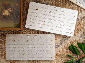 Sticker set featuring a repeating pattern of days of the week (Monday to Sunday) printed in elegant black ink on a cream-colored card, ideal for planners and journals.