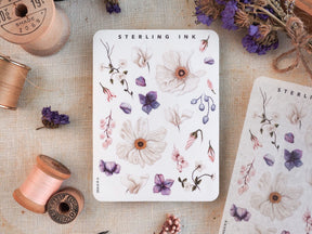 Watercolor floral sticker sheet featuring delicate botanical illustrations of pink, white, and purple blossoms with "Sterling Ink" branding.