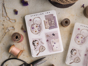Botanical sticker sheet featuring delicate illustrations of pale pink and white flowers, leaves, and elegant floral sprigs, accented with subtle silver and gold foil touches.