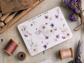 Watercolor sticker sheet featuring delicate botanical clusters of lavender, pink, and cream florals, highlighted with elegant scattered silver foil accents.