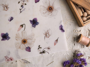 Cream vellum stationery featuring a delicate watercolor motif of scattered white and purple blossoms, buds, and detailed floral branches.
