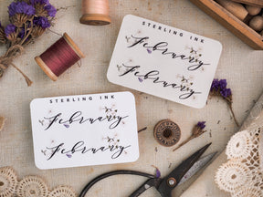 White monthly planner sticker for February featuring "Sterling Ink" in elegant script and subtle decorative floral elements for journaling.