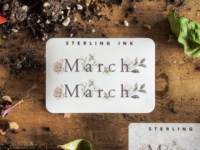 Botanical 'March' sticker design featuring the month's name surrounded by soft sage green leaves and muted pink watercolor floral accents.