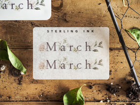 Elegant cream sticker reading "March" twice, featuring a distressed, romantic botanical wreath design with soft green sepia accents for seasonal planning.