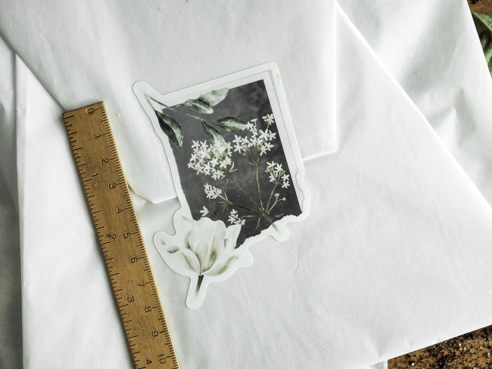 Botanical die-cut vinyl stickers featuring delicate white blossoms and lush green foliage arranged against a contrasting dark background.