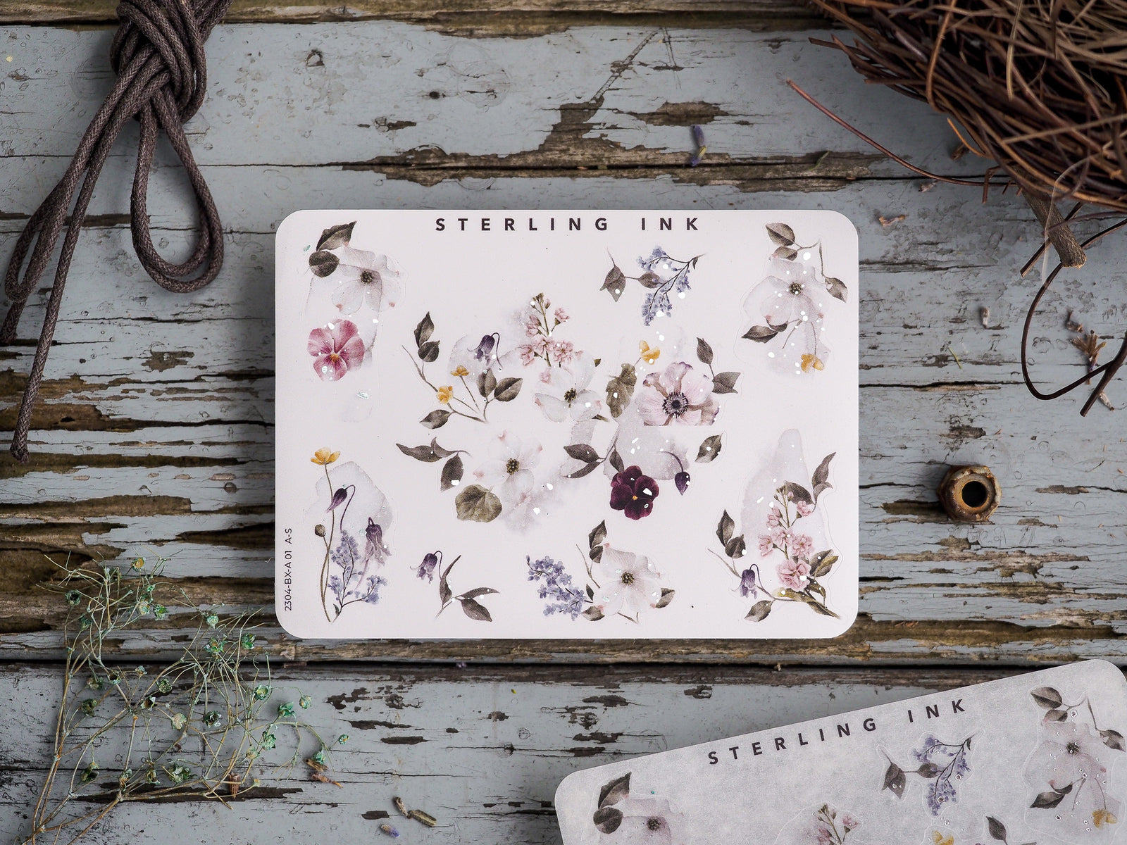 Delicate sticker sheet featuring a botanical arrangement of soft watercolor florals, including dusty purples, creams, and muted pink blossoms.