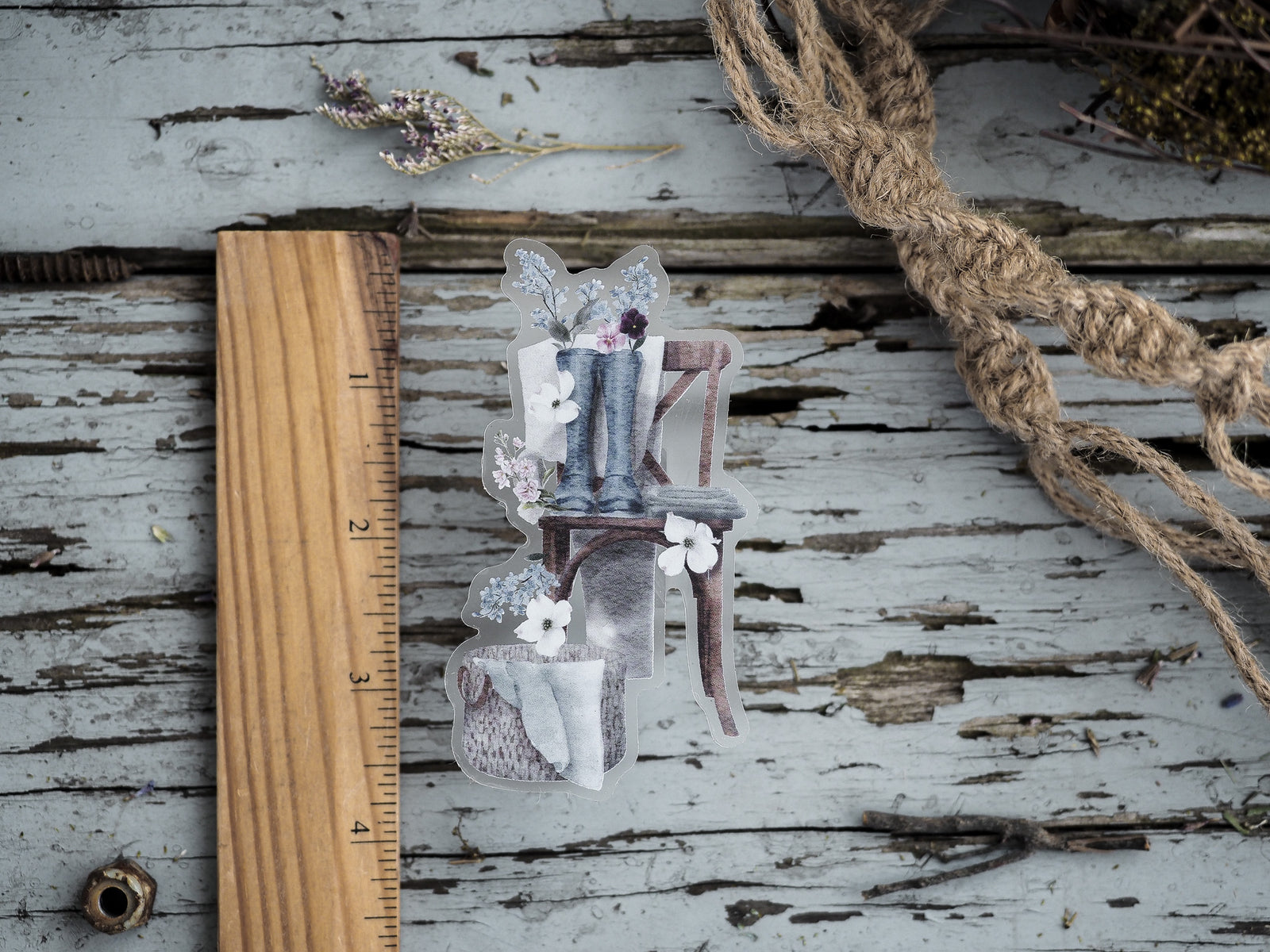 Vintage die-cut sticker showing a charming rustic wooden easel adorned with small white and purple spring flowers and delicate natural elements.