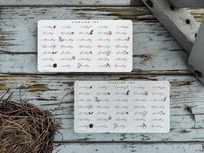 A set of three white, rectangular sticker sheets featuring a delicate, repeating pattern of purple and pink watercolor florals and foliage, labeled for planning use.