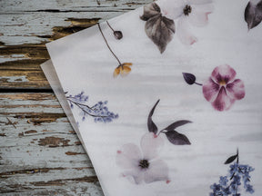 Elegant watercolor floral pattern featuring soft pastel pink, purple, and blue spring blossoms with delicate leaves.