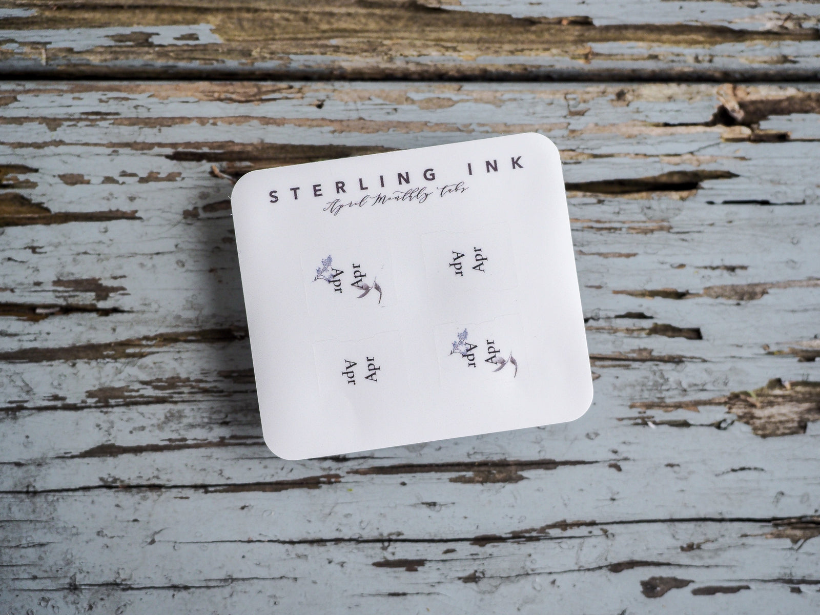 White sheet of April monthly tabs featuring the "Sterling Ink" branding and delicate printed floral accents for planning.