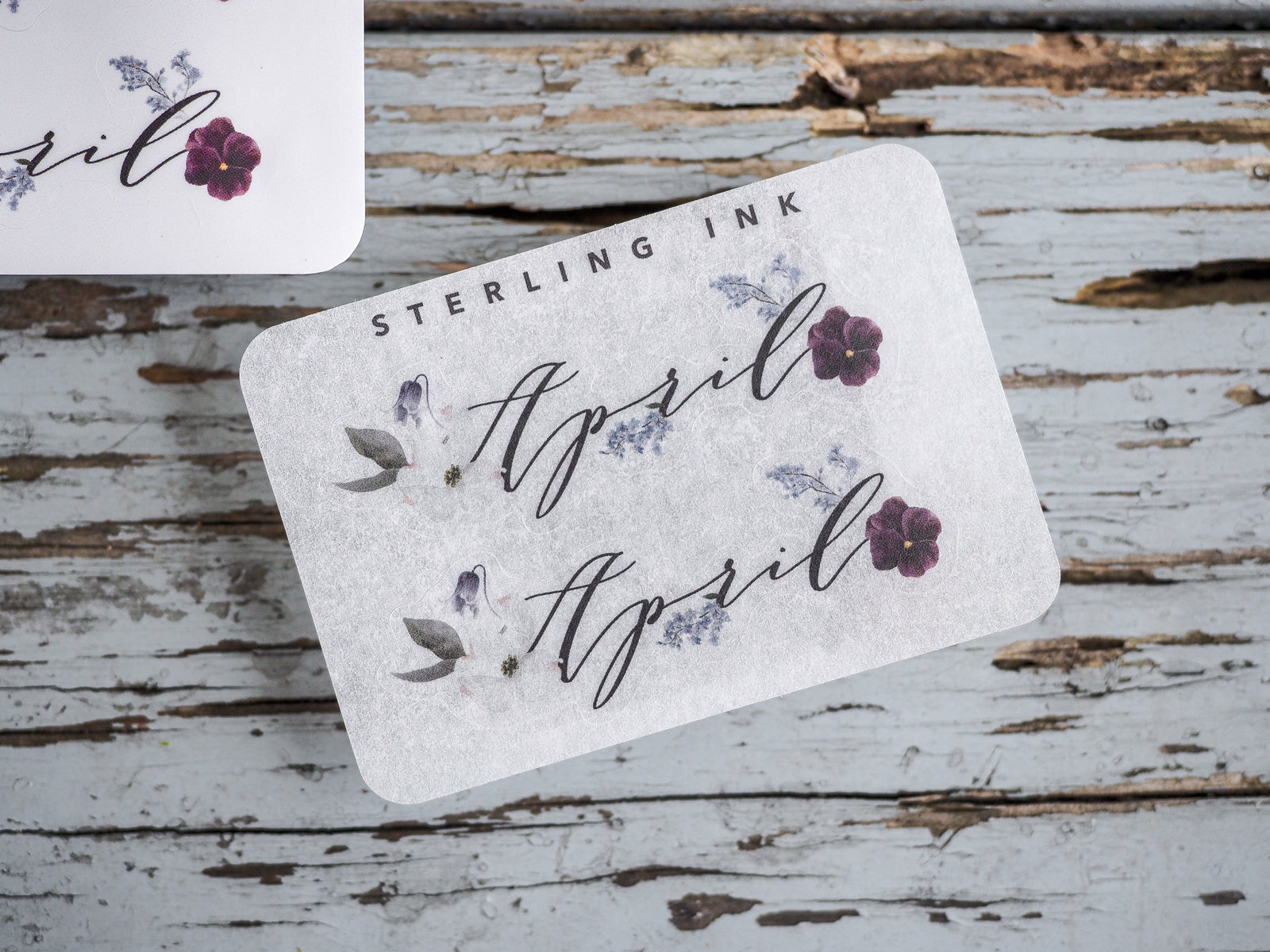 Rustic month sticker for April featuring delicate purple floral accents and the name 'April' in elegant, handwritten script.