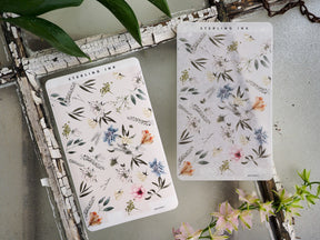 Botanical sticker sheets displaying delicate watercolor flowers in muted shades of blue, pink, and peach for journaling and scrapbooking.