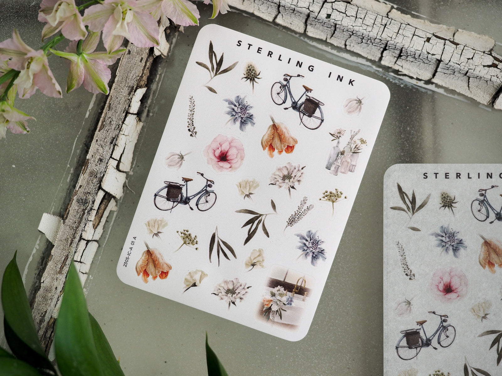A charming sticker sheet titled "Sterling Ink" featuring delicate botanical elements, including various flowers, herbs, and an antique bicycle icon.