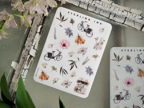 A charming sticker sheet titled "Sterling Ink" featuring delicate botanical elements, including various flowers, herbs, and an antique bicycle icon.