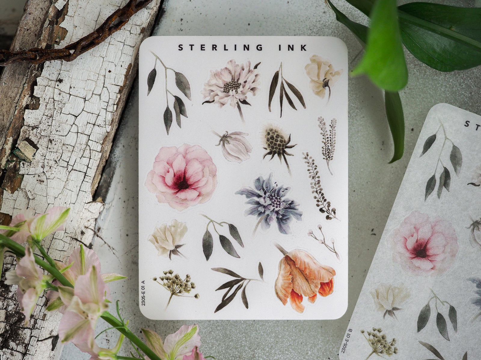 Cream-colored sticker sheet labeled "STERLING INK" featuring diverse botanical elements, including watercolor leaves, delicate flowers, and natural foliage.