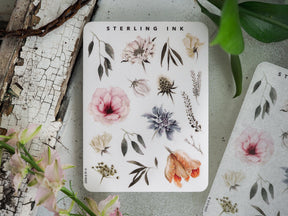 Cream-colored sticker sheet labeled "STERLING INK" featuring diverse botanical elements, including watercolor leaves, delicate flowers, and natural foliage.
