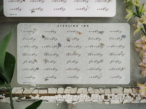 Weekly calendar stickers for May 2023, featuring the days of the week printed on white paper and decorated with delicate botanical drawings for planning and journaling.