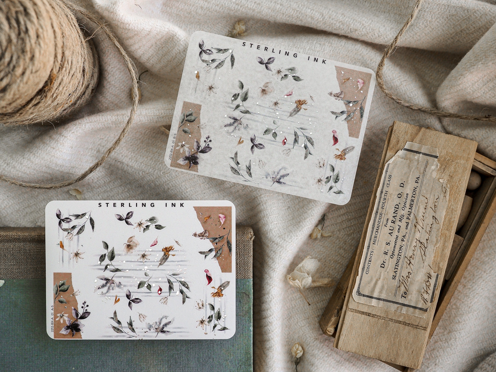 Delicate sticker sheets featuring muted botanical illustrations of dried foliage and leaves, accented with scattered sparkling silver foil detailing.