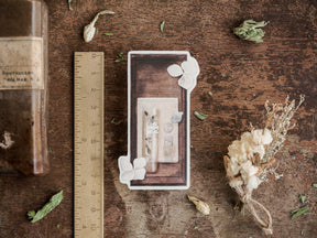 Sepia-toned botanical sticker design featuring dried herbs, delicate white blossoms, and antique apothecary illustrations suitable for seasonal journaling.