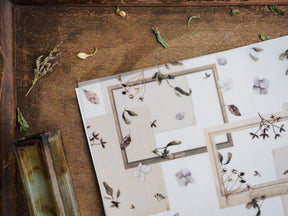 Botanical sticker set for January 2023 featuring delicate sepia-toned arrangements of dried leaves and pale flowers on creamy paper.