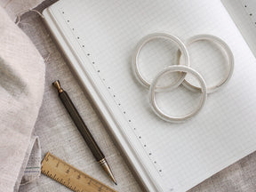 Three elegant white circular strips of time-line washi tape are displayed on a gridded planner, showing its 5mm width for hourly scheduling.