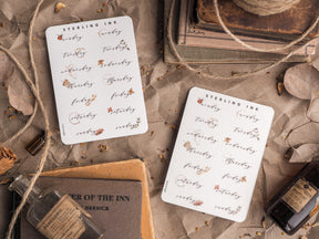 A set of elegant, white sticker sheets featuring "Weekday" labels and the calendar dates, decorated with delicate script lettering and small drawn floral accents.