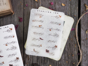 Delicate sticker set featuring handwritten days of the week and accompanying sepia-toned botanical illustrations, perfect for journal planning.