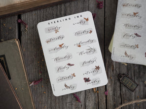 Decorative planner stickers labeling each weekday (Monday–Sunday) in rustic sepia script, accompanied by delicate printed illustrations of leaves and florals.