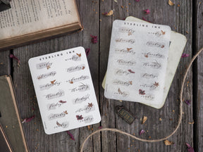 Delicate cream-colored sticker sheets featuring hand-lettered days of the week and elegant, rustic botanical leaf designs.